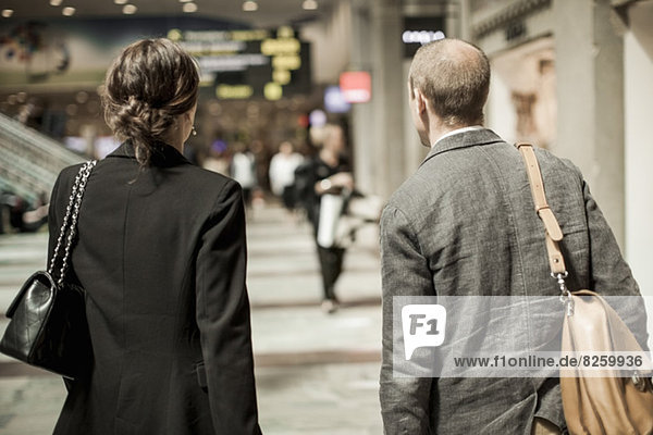 Rear view of business people with bags standing on railway station