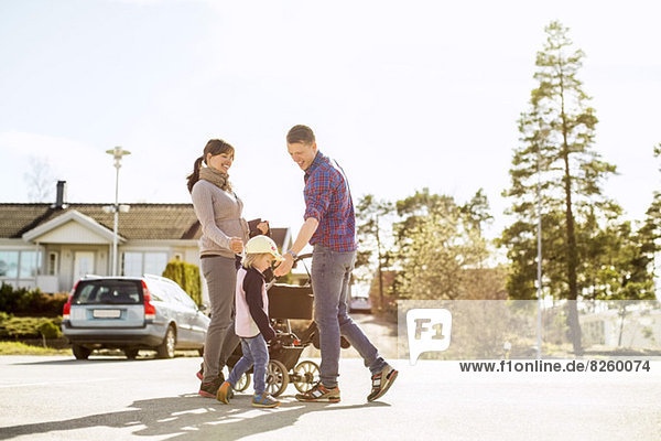 Eltern mit Kinderwagen und Tochter auf der Straße