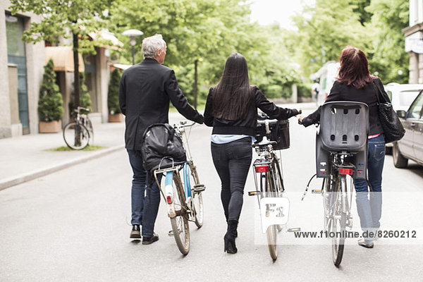 Rear view of business people with bicycles walking on street