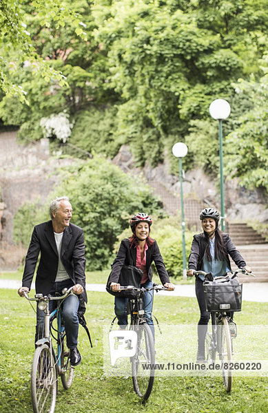 Business people riding bicycles in park
