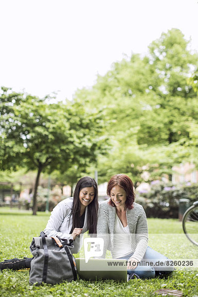 Businesswomen smiling while using laptop in park