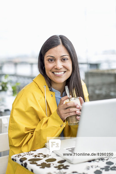 Portrait der Geschäftsfrau mit Laptop auf dem Tisch mit Milchshake im Cafe