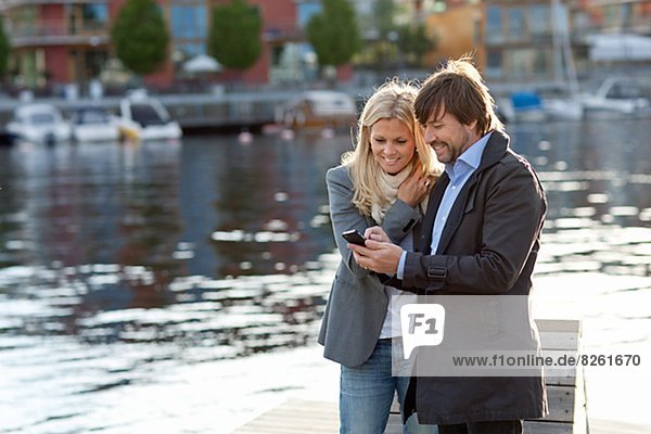 Couple standing on promenade using cell phone together