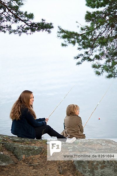 Sister and brother fishing at lake