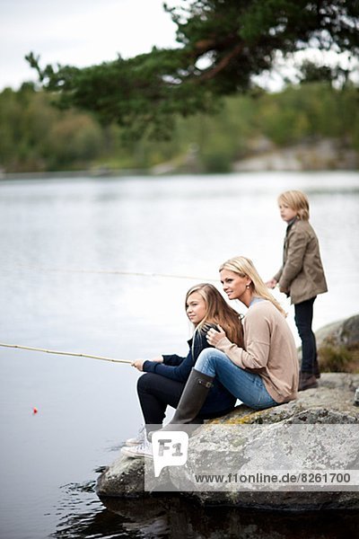 Mother with two kids fishing at lake