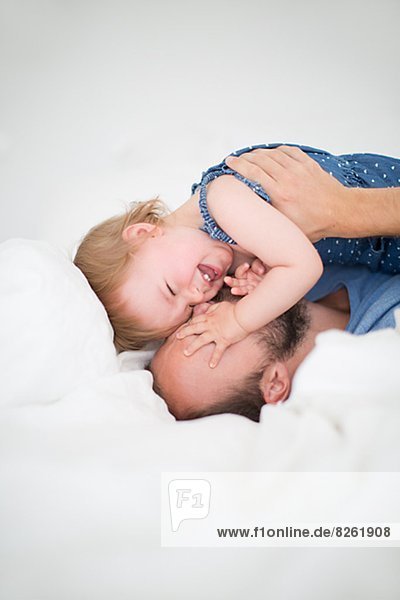 Man and little daughter lying in bed