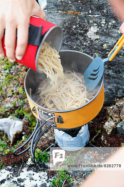 Hand adding noodles into saucepan