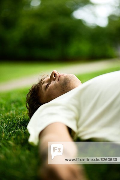 Young man lying in the grass listening to music  Sweden.