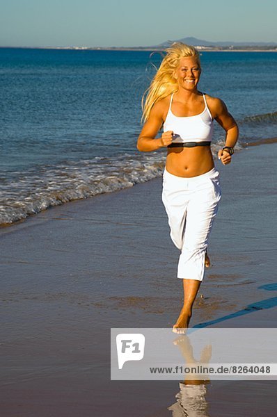 A blond woman running on a beach  Portugal.