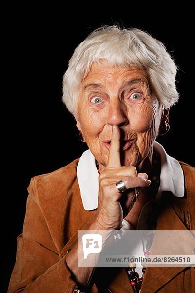 Portrait of smiling senior woman with finger on lips