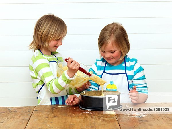 Two girls baking cake in kitchen