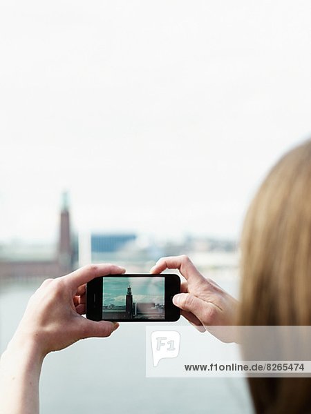 Woman photographing Stockholm City Hall with cell phone