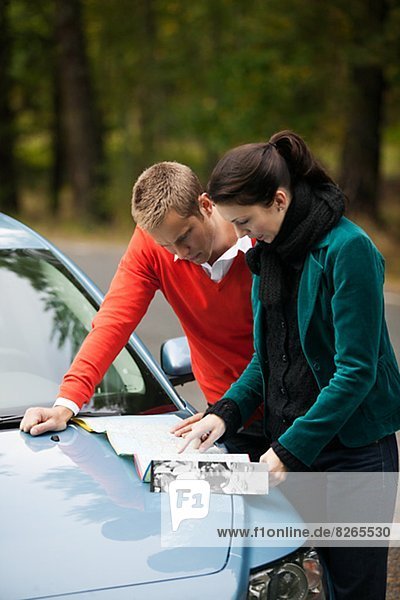 Young couple checking map on hood