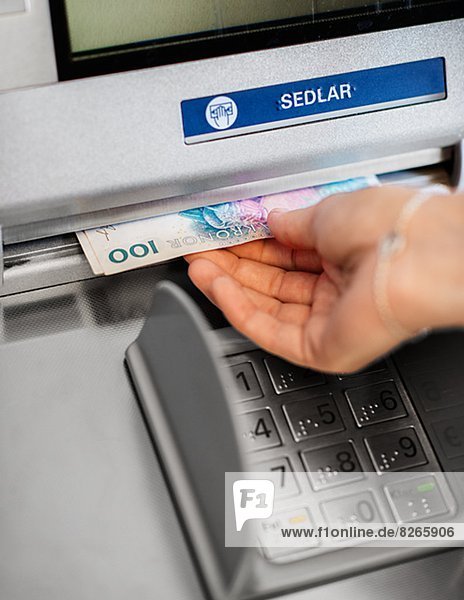 Close-up of hand taking banknotes out of cash-dispenser