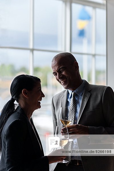 Businessman and businesswoman talking while having glass of wine