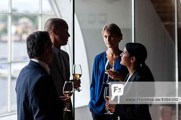 Businesspeople talking while having glass of wine