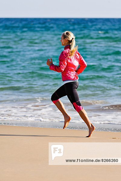 Young woman running on beach  Algarve  Portugal
