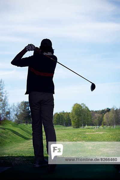 Silhouette of man playing golf
