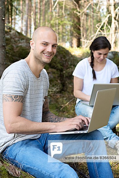 Couple in forest using laptops  Sweden
