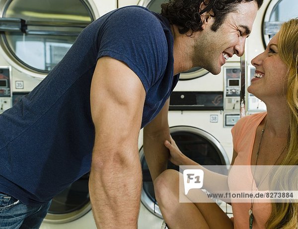 A smart young man gets cozy to a beautiful lady in San Diego coin laundromat.