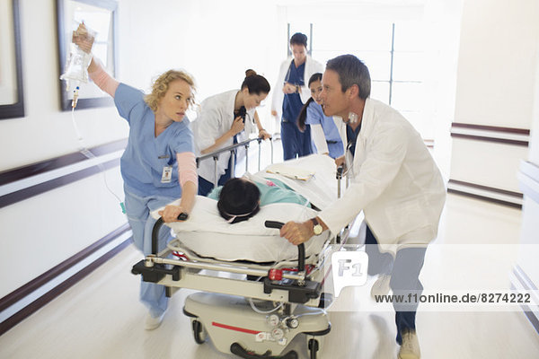Doctors rushing patient on gurney in hospital corridor