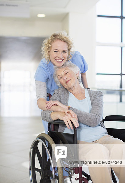 Porträt der lächelnden Krankenschwester und älteren Patientin im Rollstuhl