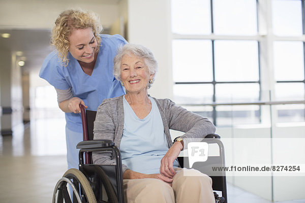 Krankenschwester und alternder Patient lächelnd im Krankenhausflur