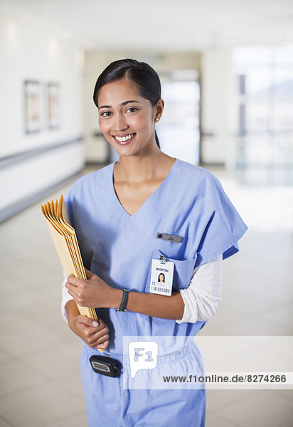 Porträt der lächelnden Krankenschwester mit Mappen im Krankenhausflur