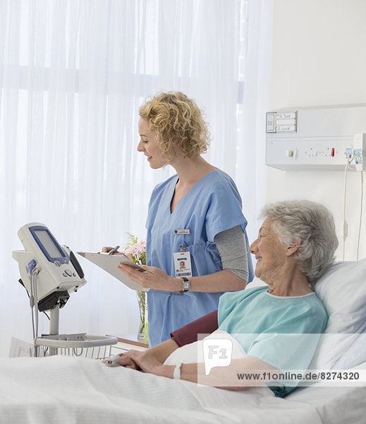 Nurse checking equipment in aging patient's hospital room