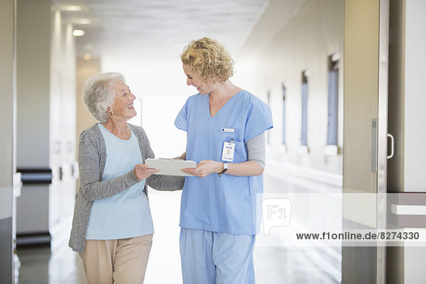 Nurse and senior patient talking in hospital corridor