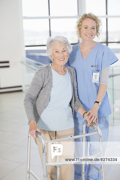 Porträt der lächelnden Krankenschwester und älteren Patientin mit Gehhilfe
