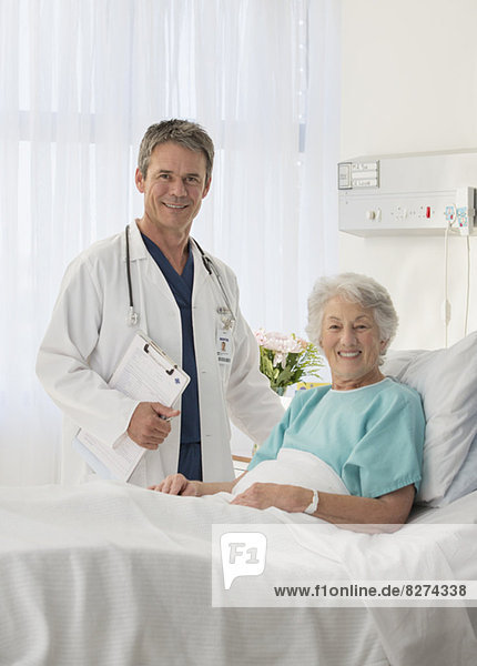 Portrait of smiling doctor and senior patient in hospital room