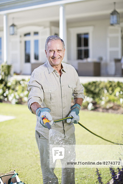 Senior Mann beim Gießen von Pflanzen im Garten