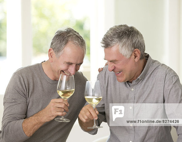 Senior men laughing and drinking white wine