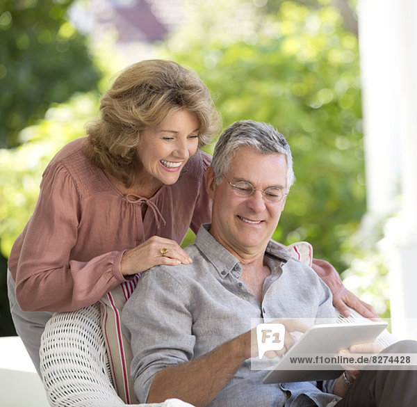 Seniorenpaar mit digitalem Tablett auf der Terrasse