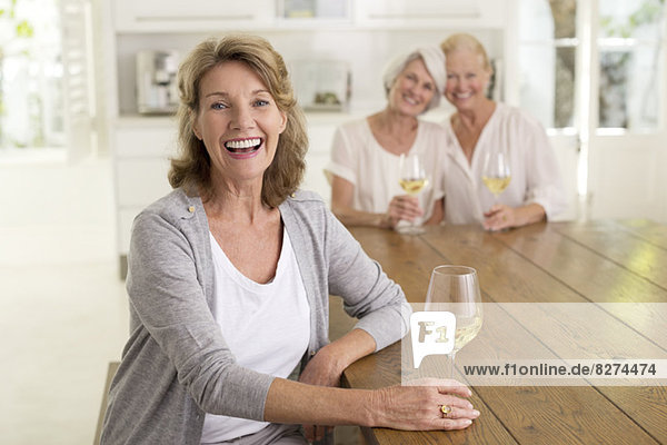 Porträt von lächelnden Seniorinnen beim Weißweintrinken