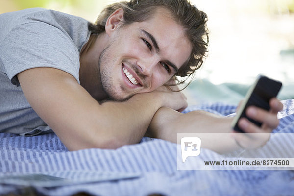 Man using cell phone on picnic blanket