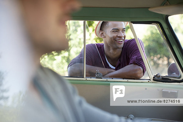 Lächelnder Mann am Fenster des Wohnmobils stehend