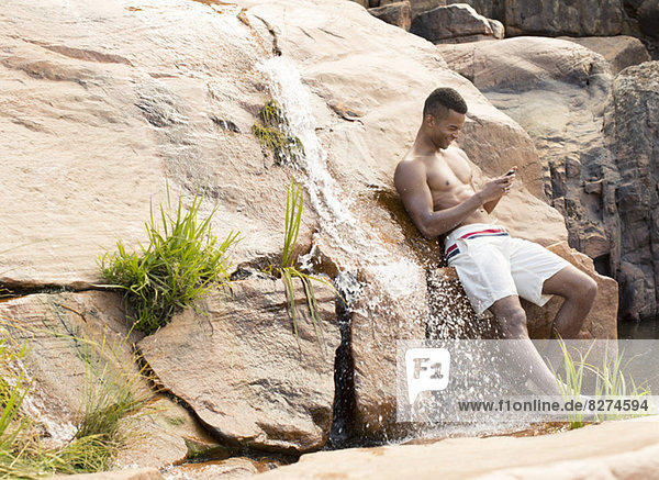 Mann mit Handy am Wasserfall