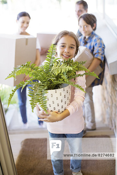 Portrait of smiling family moving belongings into house