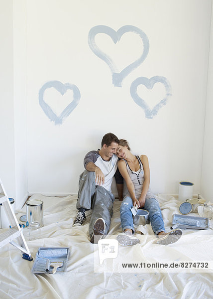 Couple painting blue hearts on wall