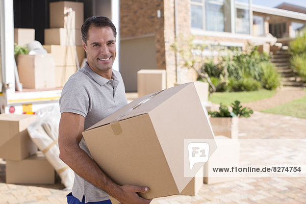 Portrait of man carrying cardboard box from moving van