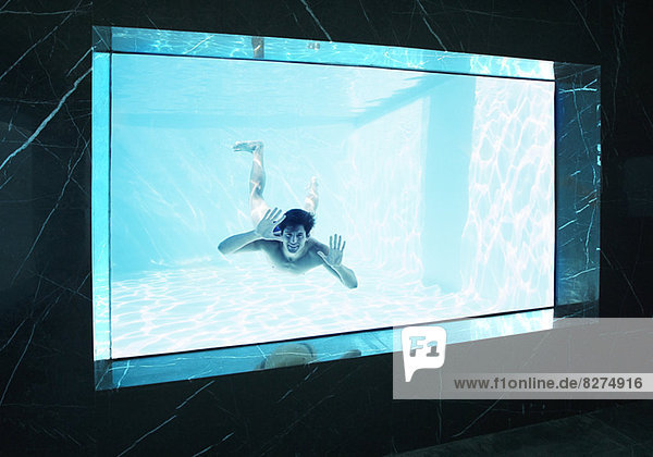 Mann schaut durchs Fenster unter Wasser im Schwimmbad