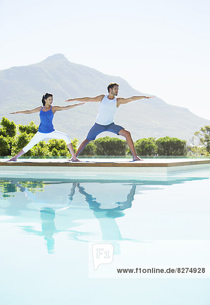 Paar beim Yoga am Pool