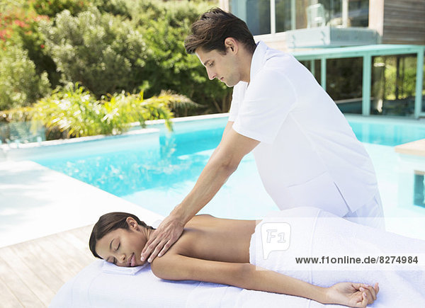 Frau erhält Massage am Pool im Spa