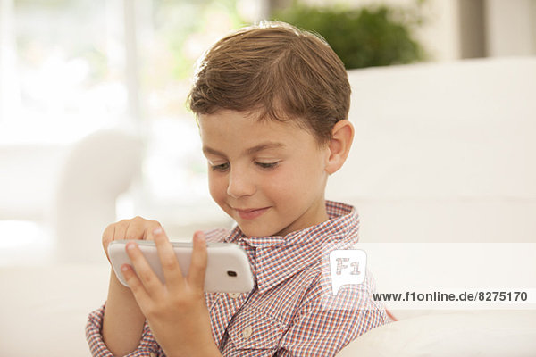 Boy using cell phone on sofa