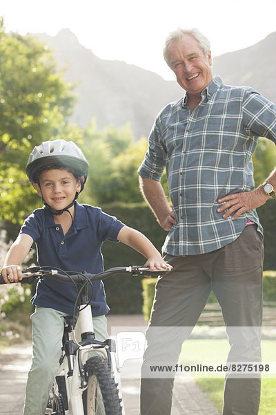 Older man teaching grandson to ride bicycle