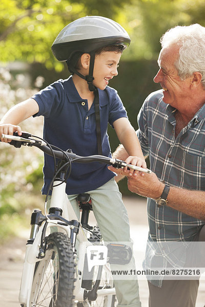 Grandfather teaching grandson to ride bicycle