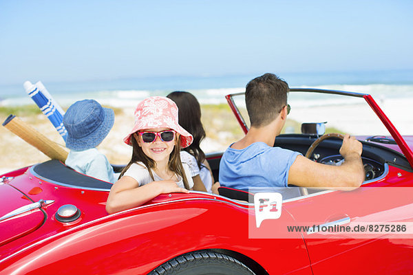 Family driving in convertible at beach
