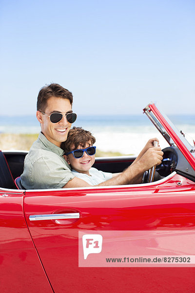 Vater und Sohn fahren Cabrio am Strand